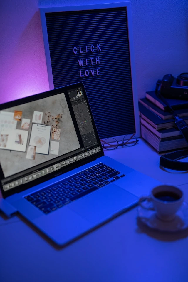 Laptop z pokazanym oprogramowaniem fotograficznym w pokoju z niebieskim światłem.